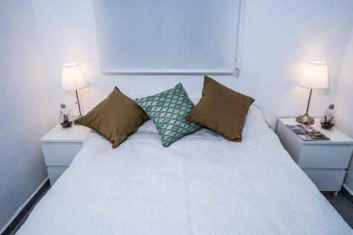 埃拉特Sea View Boutique Apartment的卧室配有带枕头和两盏灯的白色床。