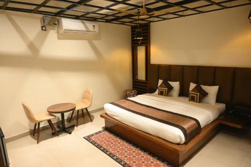 KotdwāraHotel Grand Kailash,Kotdwara的卧室配有一张床和一张桌子及椅子
