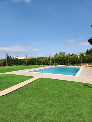 卡拉莫斯Luxe Villa Amfiario in Attica region, pool & breathtaking views!的旁边是一座绿草环绕的游泳池