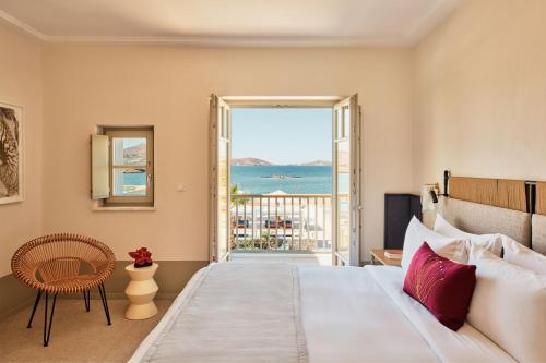 纳乌萨考斯米提斯酒店的一间卧室配有一张床,享有海景