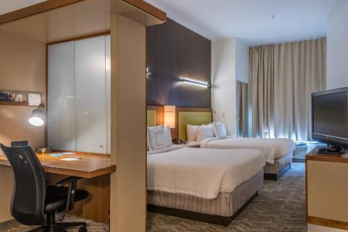 斯泰茨伯勒斯泰茨伯勒大学区春季山丘套房酒店的酒店客房设有两张床、一张桌子和一台电视。