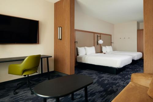 帕姆代尔Fairfield by Marriott Inn & Suites Palmdale West的酒店客房设有两张床、一张桌子和一台电视。