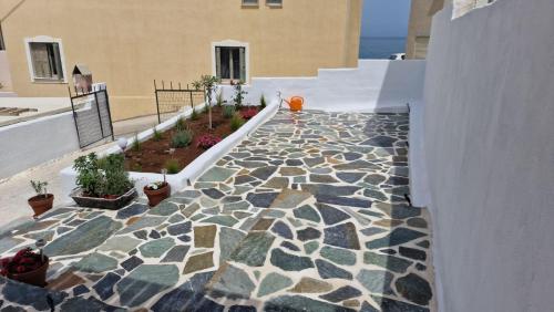 纳克索乔拉Mythical Luxury Apartment的石头人行道,在建筑上种有盆栽植物