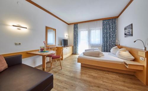 萨尔巴赫Apart-Hotel Forellenhof的配有一张床和一张书桌的酒店客房