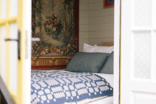 HawardenBeekeeper's Hut - Hawarden Estate的卧室配有一张挂壁挂毯的床