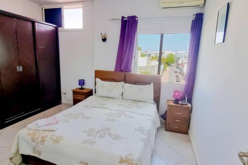 拉巴特Élégant appartement 3 chambres的一间卧室配有一张床和一个带紫色窗帘的窗户