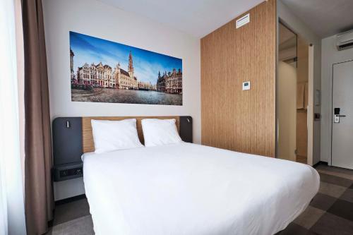 布鲁塞尔布鲁塞尔市中心便捷酒店的卧室配有白色的床和墙上的绘画作品