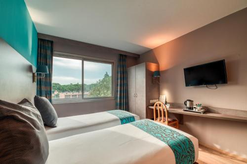 尼姆Logis NIMOTEL Hôtel Cosy的酒店客房设有两张床和窗户。