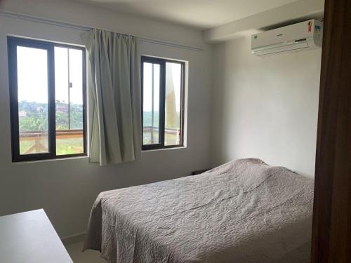 巴纳内拉斯Cond. Sonhos da Serra的一间卧室设有一张床和两个窗户。