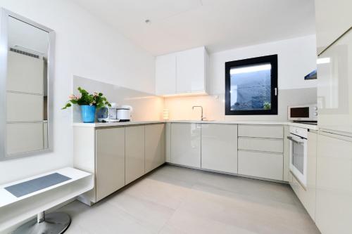 卡斯拉诺Sans Souci 1的白色的厨房配有白色橱柜和窗户