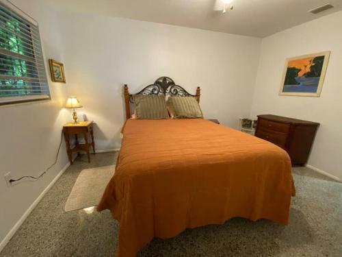 维洛海滩Vintage Vero Bungalo II的一间卧室配有一张带橙色毯子的大床