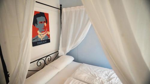 福森Old Kings Design Hostel的一间卧室配有一张带白色窗帘和绘画的床