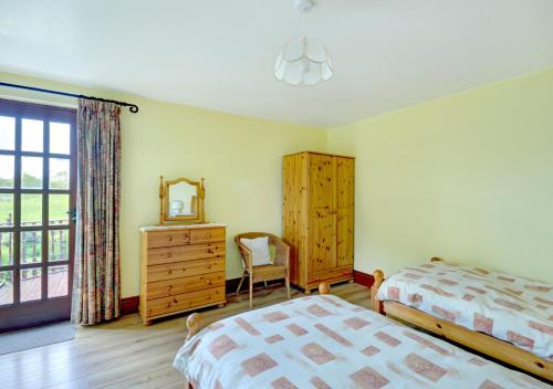 Saint MawganTrembleath Parlour的一间卧室配有两张床、一个梳妆台和镜子