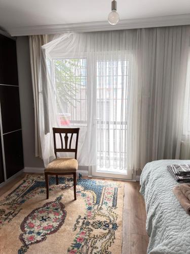 Karşıyakaan apartment in a decent neighborhood的卧室配有床、椅子和窗户。