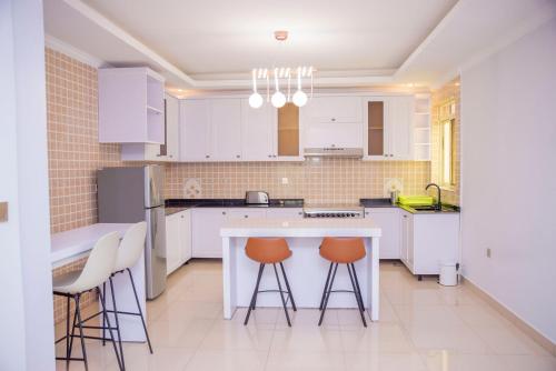基加利Grazia Apartments的厨房配有白色橱柜、桌子和凳子