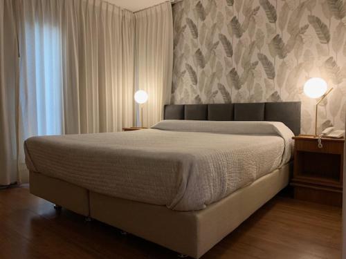 埃斯特角城雷曼索酒店的一间卧室配有一张带两盏灯和一堵墙的床。