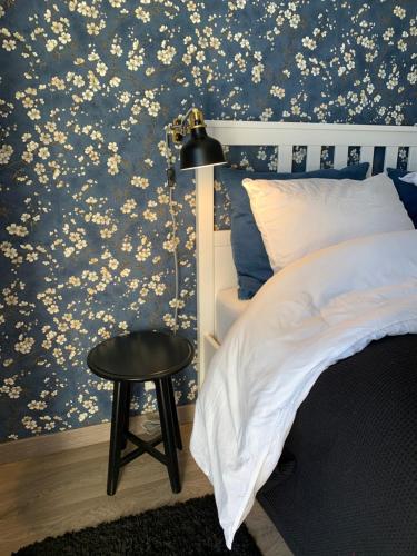 里摩日Chambre complètement indépendante !的卧室配有蓝色花卉壁纸、一张床和凳子