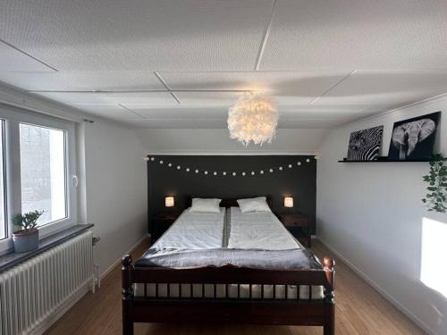 埃斯基尔斯蒂纳Modernt & rymligt sommarhus på landet- Bubbelpool的一间卧室配有一张床和一个吊灯