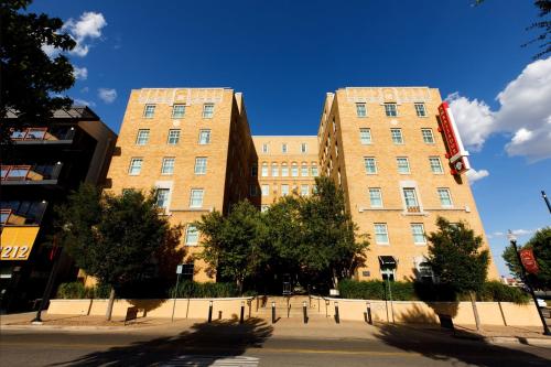 俄克拉何马城傲途格精选酒店系列之俄克拉荷马市大使酒店的两座高大的砖砌建筑,在街道前方有树木