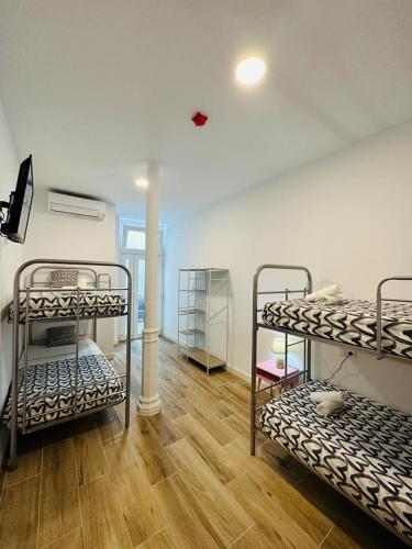韦尔瓦HOSTEL COSTA-LUZ Béjar的客房设有三张双层床,铺有木地板。