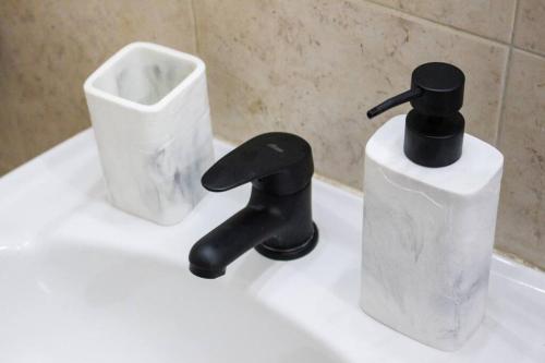 蒙得维的亚Apart Hotel Montevideo的浴室水槽,配有黑色水龙头和容器
