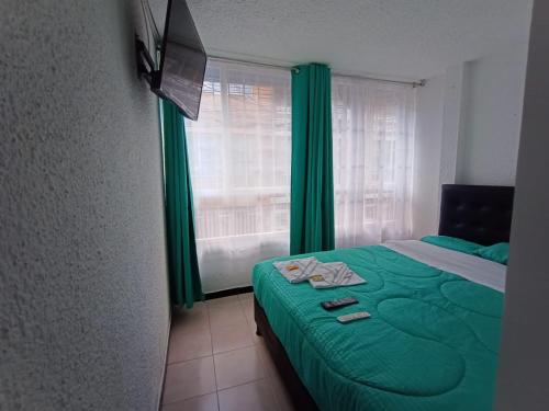 波哥大HOTEL BOGOTA AIRPORT DORADO的一间卧室设有一张绿色的床和一个窗户。
