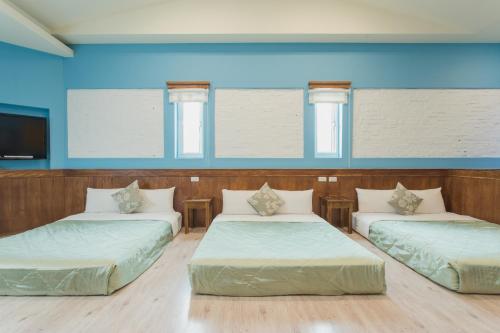 垦丁大街墾丁海園別館Hai Yuan Inn的蓝色墙壁的客房内的三张床