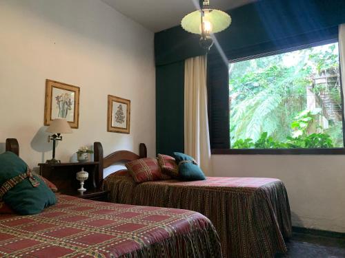 彼得罗波利斯Casa com cachoeira e rio particular的一间卧室设有两张床和大窗户