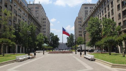 圣地亚哥Gran Departamento de tres dormitorios a pasos del metro la Moneda的建筑中间有长椅和旗帜的公园