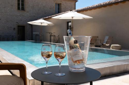 帕尔兹哈克Domaine de Panery的游泳池畔的桌子上放两杯葡萄酒