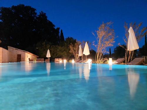 帕尔兹哈克Domaine de Panery的夜晚的蓝色海水泳池,配有遮阳伞
