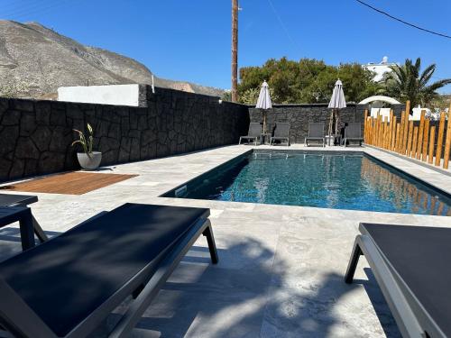 卡马利Dragonfly Villas的一个带两个长椅的游泳池,围墙旁