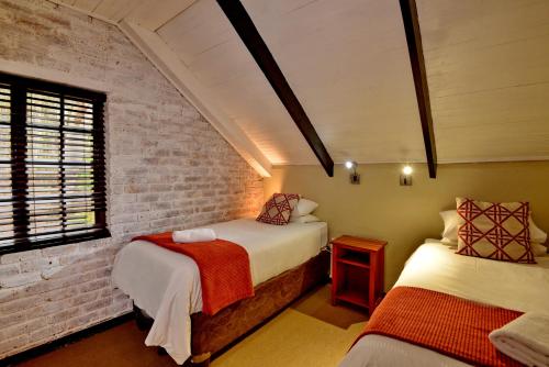 德尔斯特鲁姆Dunkeld Country & Equestrian Estate的一间卧室设有两张床和砖墙
