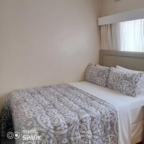 哈拉雷Neat and cosy cottage with pool - 2103的卧室配有一张带灰色和白色棉被的床
