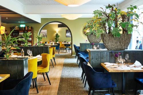 德吕特克劳斯塞尔特酒店的一间设有桌椅的餐厅,种植了植物
