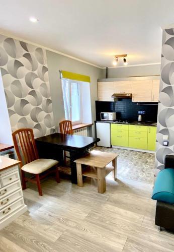 基辅Апартаменти на Поштовій площі的一间带一张桌子和两把椅子的厨房和一间带黄色橱柜的厨房