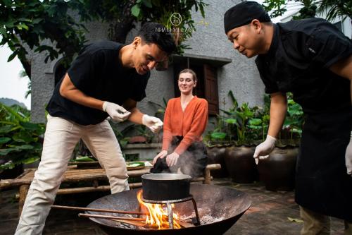 宁平Nham Village Resort的两个男人和一个女人在烤架上做饭