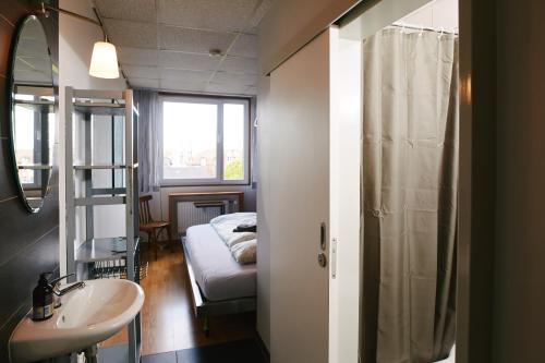 明斯特Sleep Station Hostel的一间带水槽的浴室和一张位于客房内的床