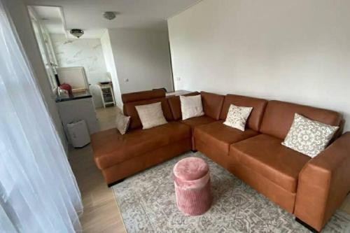 TrichtLandelijke huis in de Betuwe的客厅配有棕色沙发和粉红色凳子