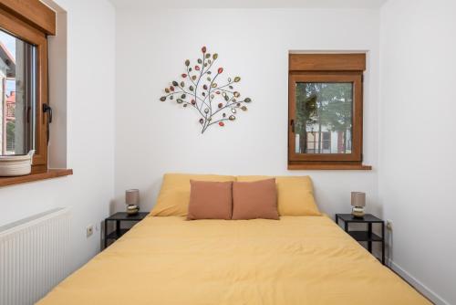 VrataApartman Roko的一间卧室配有一张带黄床单的床和两个窗户。
