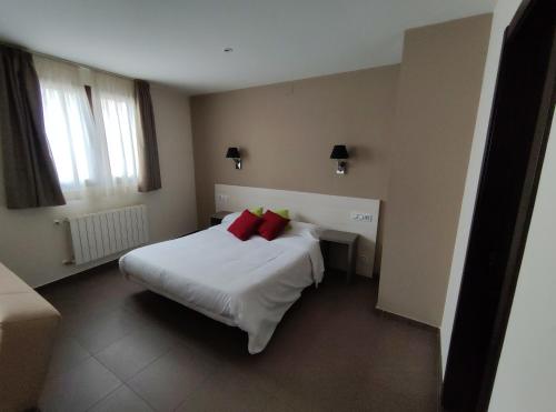 CastellfortAparthotel Castellfort的卧室配有带红色枕头的大型白色床