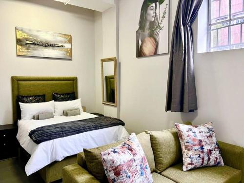 约翰内斯堡Matcha themed Apartment in City的一间卧室配有一张床、一张沙发和一张床