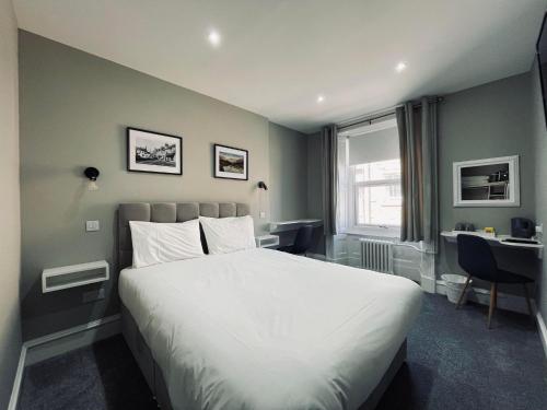 基里缪尔Airlie Arms Hotel的一间卧室配有一张床、一张书桌和一个窗户。