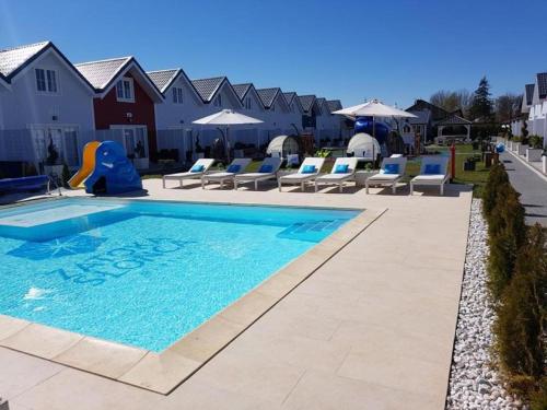 梅尔诺Zatoka Slonca - Domki z basenem, WiFi i parking w cenie!的度假村的游泳池配有椅子和遮阳伞