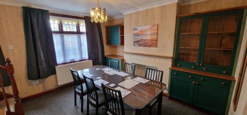 UpwellVH, 4 BR House, Upwell, Wisbech的用餐室配有桌椅和绿色橱柜