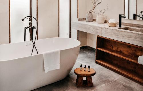 阿莱曼Le Sidi - A TLT Signature Hotel的一间带白色浴缸和木凳的浴室
