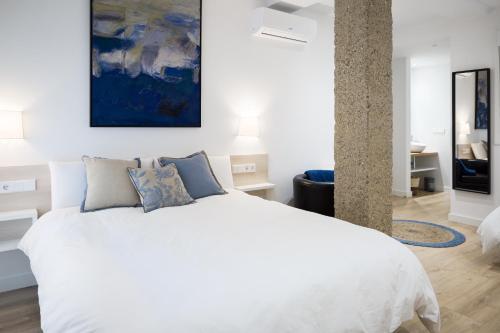 潘普洛纳CARPE DIEM - Disfruta a lo grande的卧室配有白色的床,墙上挂有蓝色的画作