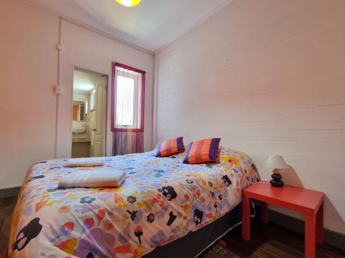 瓦尔帕莱索Meraki Hostel - Cerro Alegre - Valparaíso的一间卧室配有一张床和一张红色的桌子