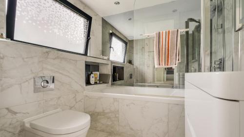 伦敦Cosy Luxurious Family Home的浴室配有卫生间、浴缸和水槽。