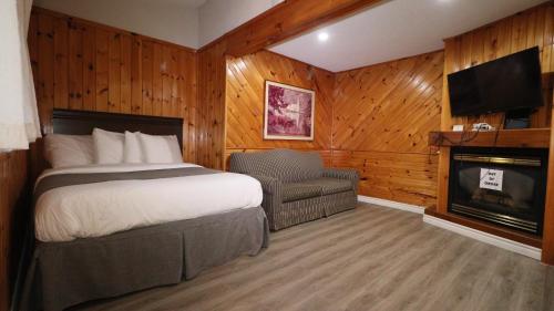 Dwight阿冈昆湖滨旅馆的一间卧室配有一张床、一把椅子和一个壁炉